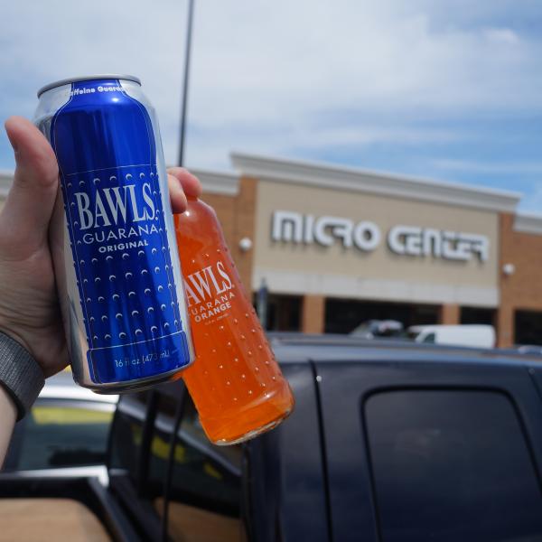 Hand holding BAWLS soda bottles